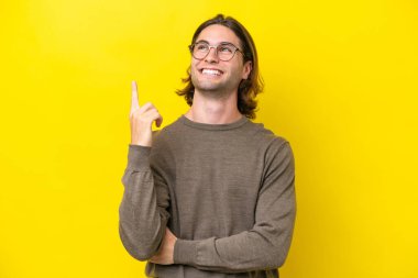 Caucasian handsome man isolated on yellow background pointing up a great idea