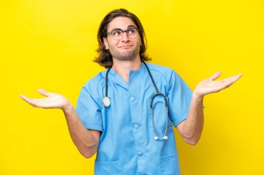 Sarı arka planda izole edilmiş genç cerrah ellerini kaldırırken kuşkuları var.