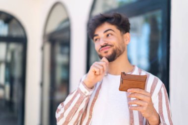 Açık havada cüzdan tutan yakışıklı bir Arap.