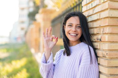 Dışarıdaki genç kadın parmaklarıyla işaret veriyor.