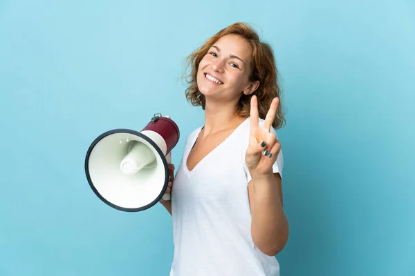 Jonge Georgische Vrouw Geïsoleerd Blauwe Achtergrond Met Een Megafoon Glimlachend — Stockfoto