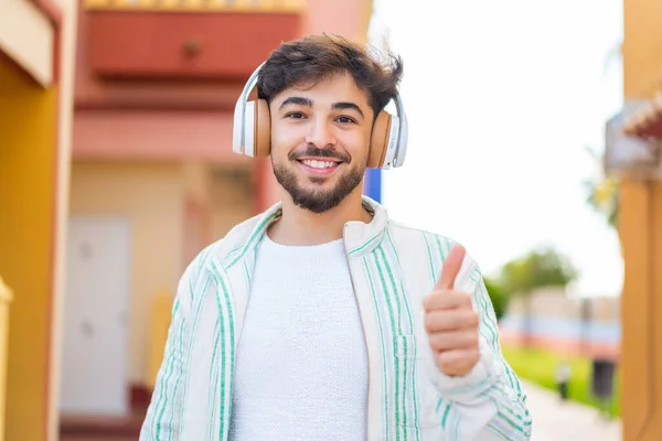 Knappe Arabische Man Buiten Luisterend Naar Muziek Met Duim Omhoog — Stockfoto