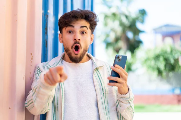Fešák Arab Muž Pomocí Mobilního Telefonu Venku Překvapen Ukazuje Dopředu — Stock fotografie