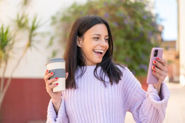 Dışarıda Cep Telefonu Kullanan Elinde Mutlu Bir Ifadeyle Kahve Tutan — Stok fotoğraf