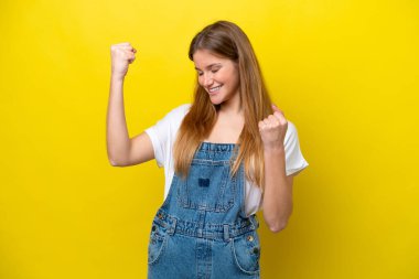 Young caucasian woman isolated on yellow background celebrating a victory clipart