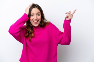 Beyaz arka planda izole edilmiş genç beyaz kadın şaşırmış ve işaret ediyor.