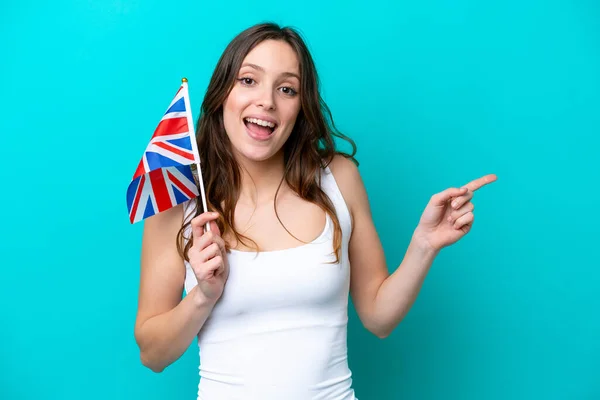 青い背景に英語の旗を持っている若い白人女性は驚いて 側に指を指す — ストック写真