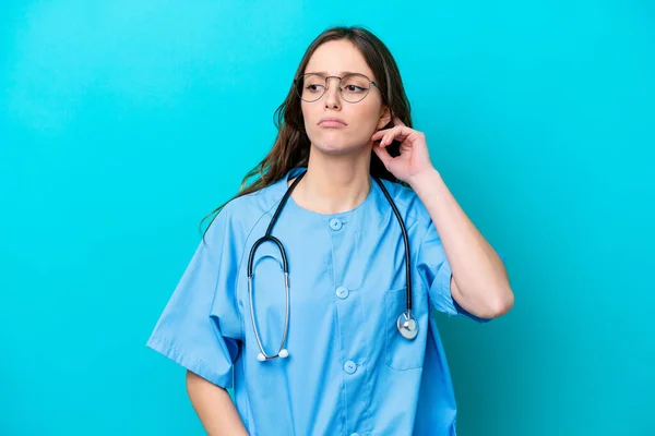 Junge Chirurgin Ärztin Isoliert Auf Blauem Hintergrund Mit Zweifeln — Stockfoto