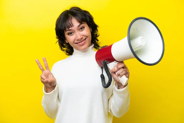 Mladá Argentinská Žena Izolovaná Žlutém Pozadí Drží Megafon Usmívá Ukazuje — Stock fotografie