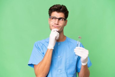 Genç dişçi arka planda araçlar tutuyor. Şüpheleri ve düşünceleri var.