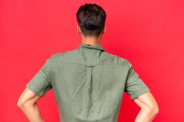 Kafkasyalı yakışıklı genç adam kırmızı arka planda izole edilmiş.