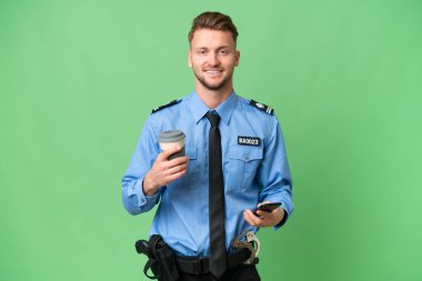 Arka planda izole edilmiş genç bir polis kahve ve bir cep telefonu tutuyor.
