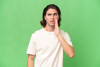 Genç beyaz adam yeşil krom arka planda izole edilmiş. Yan tarafa bakarken sürpriz bir jest yapıyor.