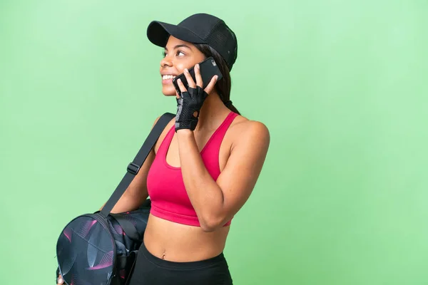 若いですスポーツアフリカ系アメリカ人女性とスポーツバッグで隔離された背景携帯電話との会話を維持 — ストック写真