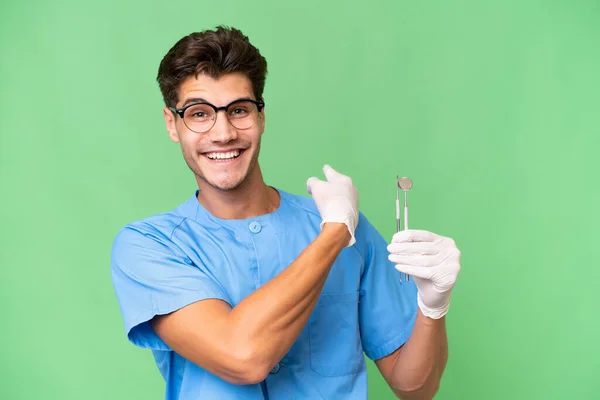 Jovem Dentista Homem Segurando Ferramentas Sobre Fundo Isolado Apontando Para — Fotografia de Stock