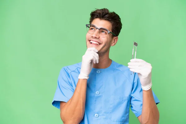 Jovem Dentista Homem Segurando Ferramentas Sobre Fundo Isolado Olhando Para — Fotografia de Stock