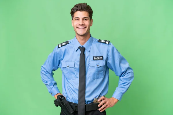 Młody Policjant Odizolowanym Tle Pozujący Rękami Biodrach Uśmiechnięty — Zdjęcie stockowe