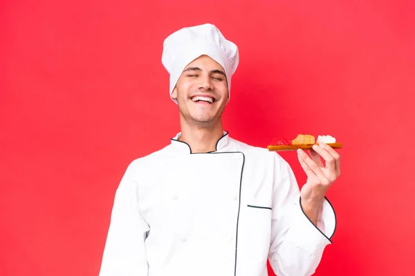 Joven Chef Caucásico Hombre Sosteniendo Sashimi Aislado Sobre Fondo Rojo —  Fotos de Stock