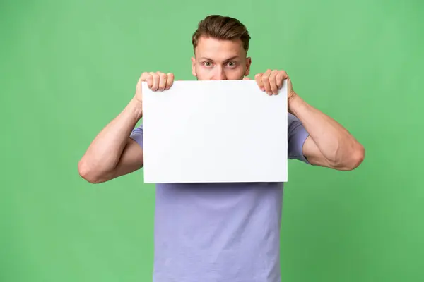 Young Blonde Caucasian Man Isolated Background Holding Empty Placard Hiding — Stock Photo, Image