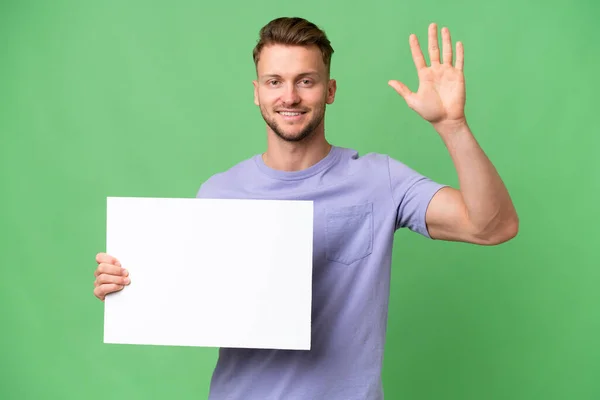 Young Blonde Caucasian Man Isolated Background Holding Empty Placard Saluting — Stock Photo, Image