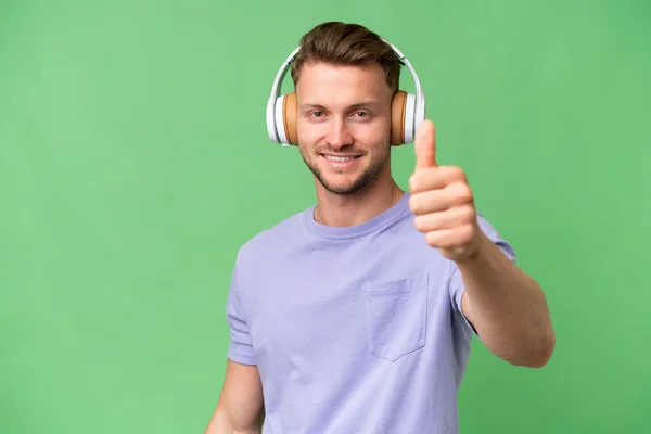 Jong Blond Kaukasische Man Geïsoleerde Achtergrond Luisteren Muziek Met Duim — Stockfoto