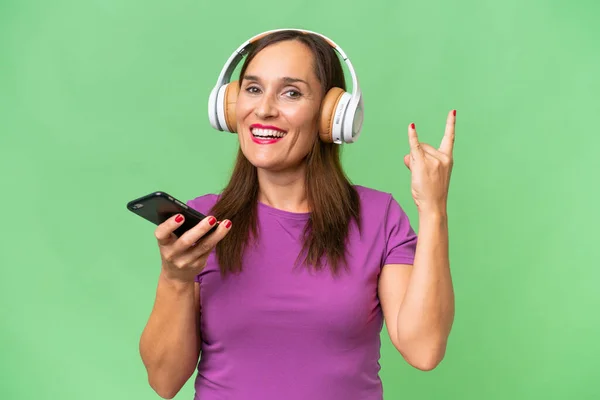 Кавказька Жінка Середнього Віку Над Ізольованим Фоном Слухає Музику Мобільним — стокове фото