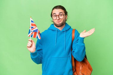 Genç yakışıklı bir adam İngiltere bayrağını soyutlanmış arka planda tutarken şüphe içinde el kaldırıyor.