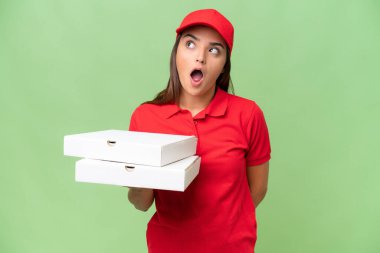 İş üniformalı beyaz bir kadın yeşil krom arka planda izole edilmiş pizza kutularını topluyor.