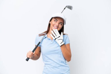 Beyaz arka planda golf oynayan beyaz tenli genç bir kadın gülümserken yukarı bakıyor.