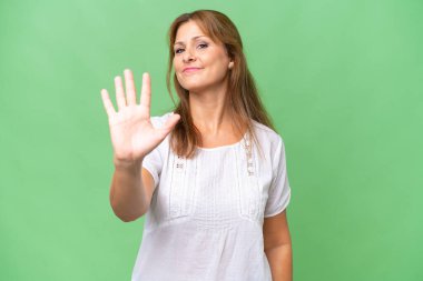 Orta yaşlı beyaz kadın tecrit edilmiş arka planda beş parmaklı sayıyor.