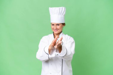 Orta yaşlı aşçı kadın münzevi bir arka planda bir konferanstan sonra alkışlıyor.