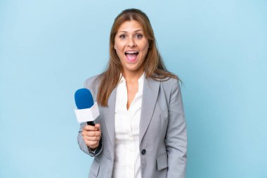 Orta yaşlı televizyon sunucusu, mavi arka planda sürpriz bir yüz ifadesi olan kadın.