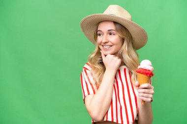 Kornet dondurması olan genç bir İngiliz kadın izole edilmiş arka planda bir fikir üretiyor ve bir tarafa bakıyor.