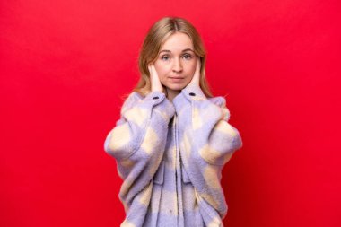 Young English woman isolated on red background frustrated and covering ears