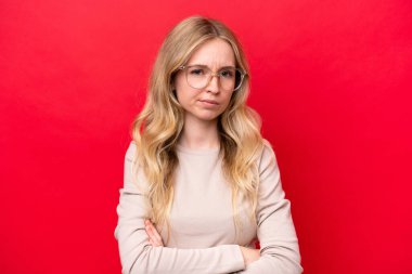Kırmızı arka planda izole edilmiş genç bir İngiliz kadın Gözlük ve kollar çapraz