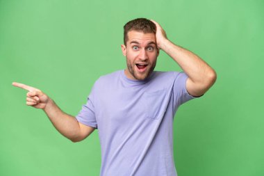 Yeşil krom arka planda izole edilmiş yakışıklı beyaz adam şaşırdı ve parmağını yana çevirdi.