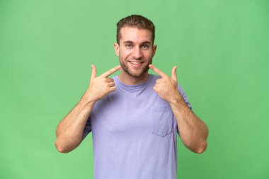 Yeşil krom arka planda izole edilmiş yakışıklı beyaz bir adam baş parmak hareketi yapıyor.