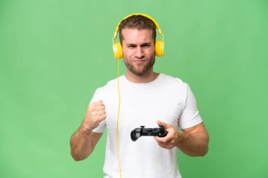 Yeşil krom arka planda izole edilmiş bir video oyunu kontrolörüyle oynayan genç yakışıklı adam.
