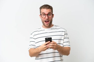 Beyaz arka planda izole edilmiş yakışıklı beyaz adam şaşırdı ve bir mesaj gönderiyor.