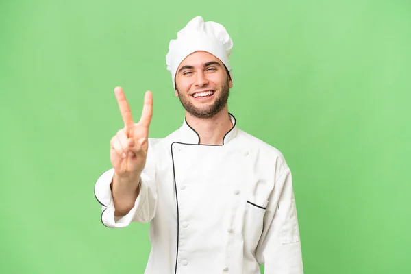 Junger Gutaussehender Koch Über Isoliertem Hintergrund Lächelt Und Zeigt Siegeszeichen — Stockfoto