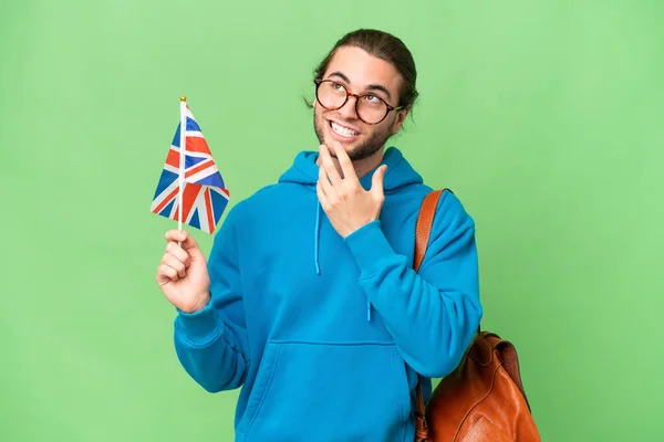 年轻英俊男子举着英国国旗 背景孤寂 微笑着抬起头来 — 图库照片