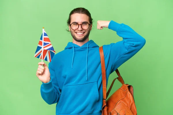 年轻英俊男子举着英国国旗 身披孤立的背景 做着强有力的手势 — 图库照片