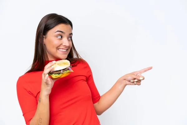 Young Caucasian Woman Holding Burger Isolated White Background Pointing Side — Stock Photo, Image