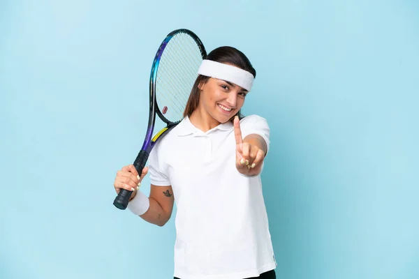 年轻的网球选手被蓝色背景隔离 露出并举起了一个手指 — 图库照片