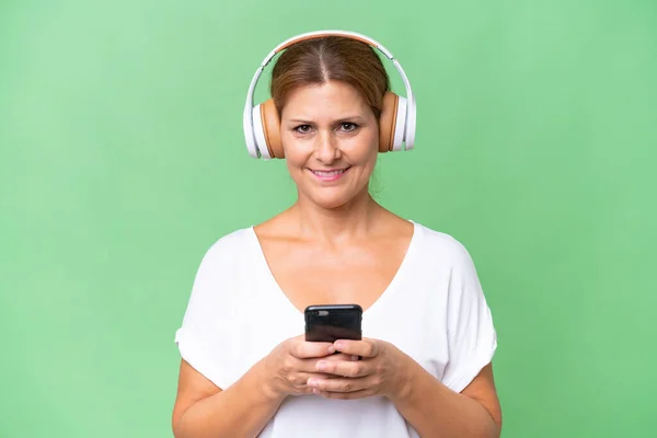 Middle Aged Caucasian Woman Isolated Background Listening Music Mobile Looking — Stock Photo, Image