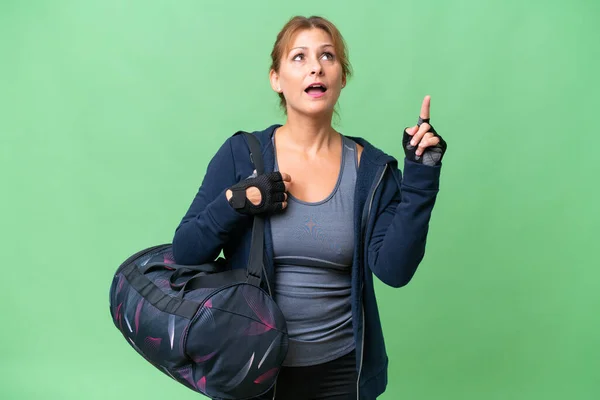中年スポーツ女性とともにスポーツバッグ上の隔離された背景を指摘し 驚いて — ストック写真