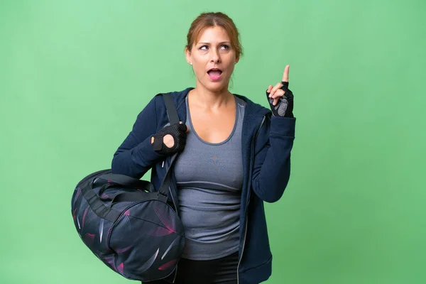 指を持ち上げながら解決策を実現しようとする孤立した背景にスポーツバッグを持つ中高年のスポーツ女性 — ストック写真