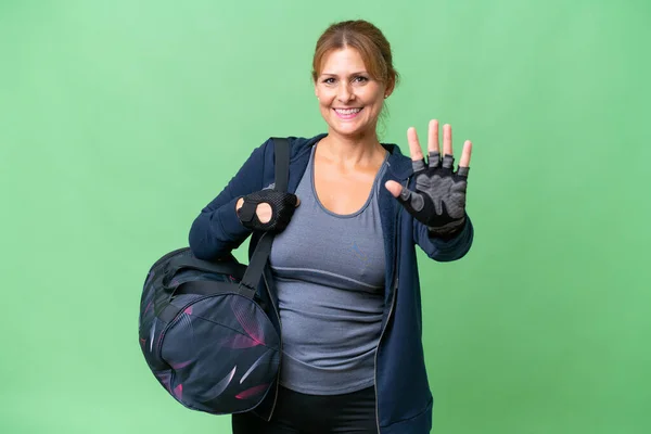 Middle-aged sport woman with sport bag over isolated background counting five with fingers