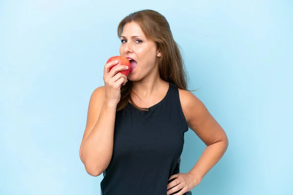 Medelålders Kaukasiska Kvinna Isolerad Blå Bakgrund Äta Ett Äpple — Stockfoto