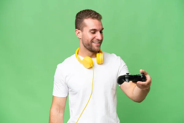 Νεαρός Όμορφος Άντρας Παίζει Ένα Χειριστήριο Βιντεοπαιχνιδιών Απομονωμένο Πράσινο Φόντο — Φωτογραφία Αρχείου